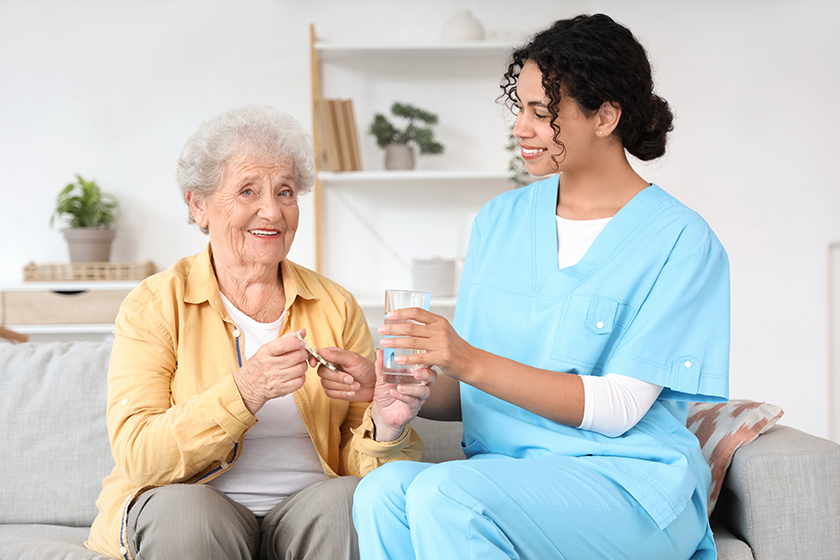 young-african-american-female-medical-worker-giving-elderly-woman-pills